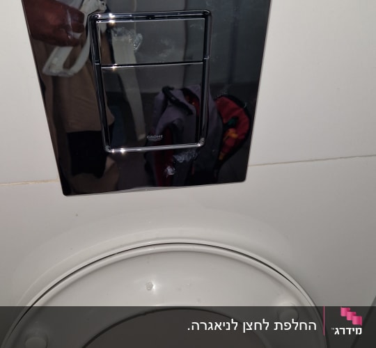 לחצן הדחה מעל אסלה בחדר אמבטיה